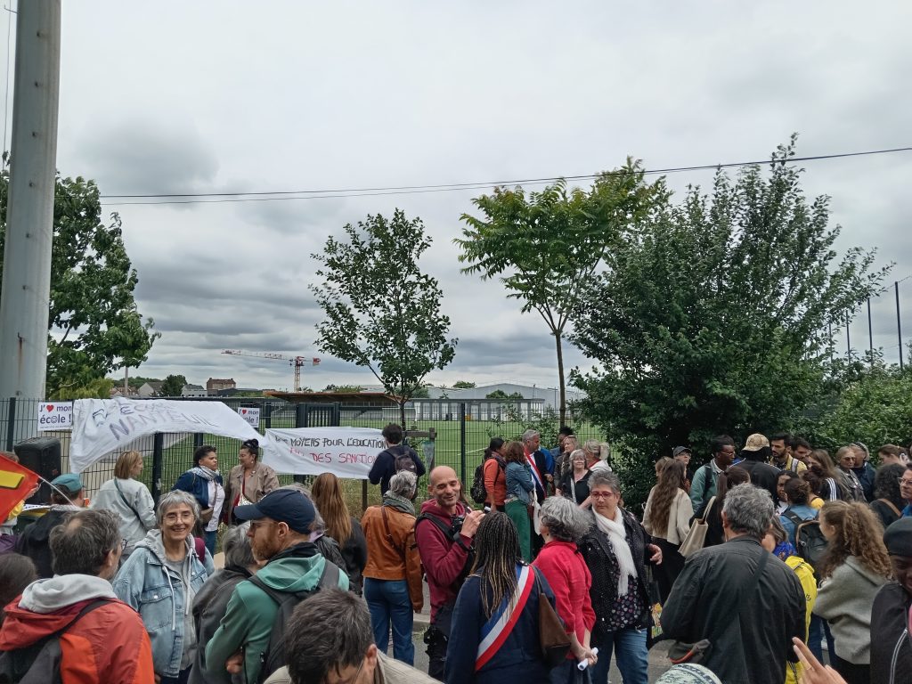 Groupe de personnes rassemblées devant le grillage avec les banderoles « Solidarité école Nanteuil », « J’aime mon école » et « Des moyens pour l’éducation, pas des sanctions »